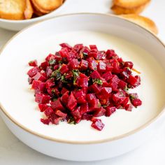 a white bowl filled with chopped beets next to some toasted baguettes