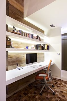 a computer desk with a monitor on top of it next to a bookshelf