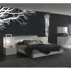 a bed room with a neatly made bed and a tree decal on the wall