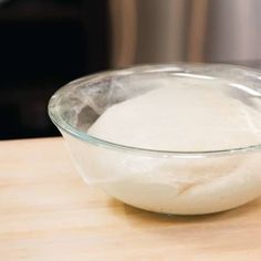 a glass bowl filled with flour on top of a wooden table