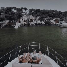 two people laying on the back of a boat