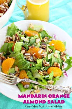 there is a salad with oranges and almonds on the plate next to a glass of orange juice