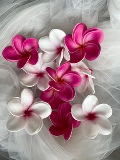 pink and white flowers are arranged in the middle of a tulle veiled background