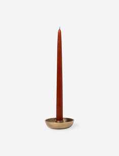 a red candle sitting on top of a metal bowl with a gold ring around it