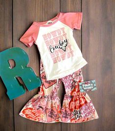 Love, love, love this Howdy Cowboy Bell Bottom outfit! Absolutely adorable! I hope you and your lil Cowgirl agree! 💕 A fun, comfortable western girl outfit featuring a baseball style t-shirt and the cutest western print pink bell bottom pants!  We have tons of Western Bell Bottom outfits ready to ship today! 😃 Always, FREE Shipping with $35 purchase! TTS. 95% Cotton, 5% Spandex. Machine washable and dryable More Razels! Shop tons of girls western boutique outfits. Cute Letter Print Playwear Sets, Cute Pink Sets With Letter Print, Cute Pink Letter Print Sets, Western Bell Bottom Outfit, Bell Bottom Outfit, Bell Bottom Outfits, Bottom Outfits, Outfit Cowgirl, Bell Bottoms Outfit