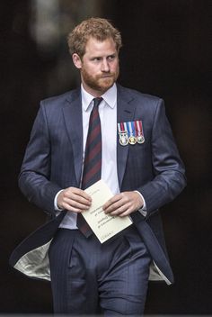 a man in a suit and tie walking with medals on his lapel while holding a note