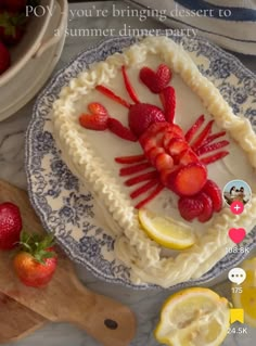 there is a cake decorated with strawberries and lemons on the plate next to it