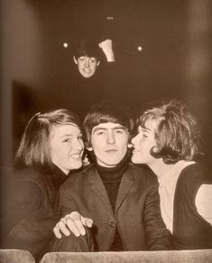 three people sitting next to each other in front of a man with his face close to the woman's head