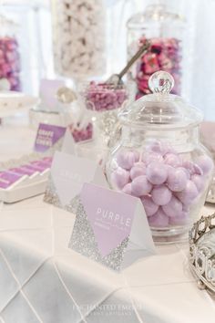 a table topped with lots of pink and white candies next to a glass jar filled with candy