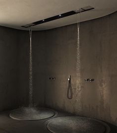 two circular shower heads with water spouting from them in a dimly lit room