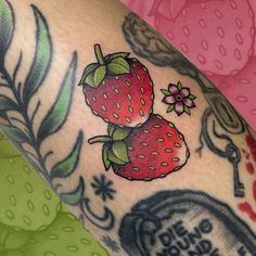 a close up of a person's arm with tattoos on it and two strawberries