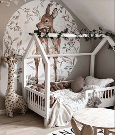 a child's room with a bed, table and giraffe mural on the wall