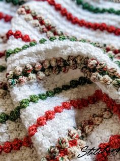 a crocheted blanket with red, green and white stripes on it's edges