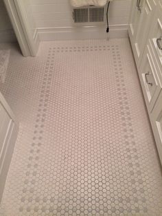 a white bathroom with hexagonal tiles on the floor