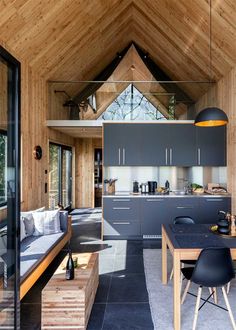 a kitchen and living room are separated by a vaulted ceiling with wood paneling on the walls