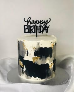 a black and white birthday cake with gold sprinkles on it's top