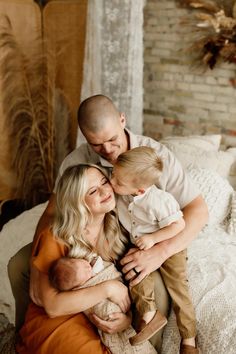 a man and woman holding a baby while sitting on a bed