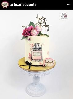 a white cake with pink flowers on top and happy birthday written on the side in black writing