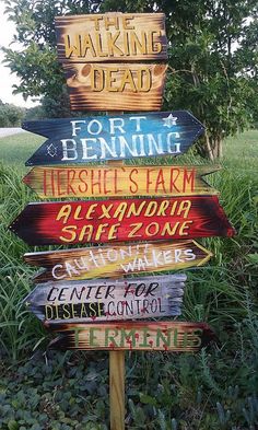 a wooden sign with many different signs on it's side in front of some grass