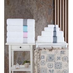 a stack of white towels sitting on top of a table next to a towel rack