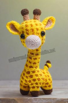 a crocheted giraffe toy sitting on top of a wooden table next to a wall