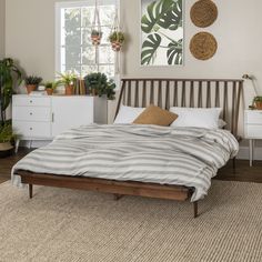 a bed sitting on top of a wooden floor next to a white dresser and window