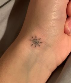 a small sun tattoo on the foot of a woman's left foot, with an arrow in the middle