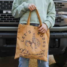 This stylish Let's Rodeo Canvas Tote Bag is the perfect standout accessory for those looking to make a statement! Crafted from sturdy canvas, the tote will stand up to daily wear and tear and will keep your belongings safe and secure. The warm mustard tone amplifies the Let's Rodeo message for a truly inspirational look. Who's ready to Rodeo? Cotton canvas tote with long shoulder strap, and hand straps. Snap closure at top, and a zip pocket inside, perfect to store your small items! 14"x14"Handw Tan Logo Coated Canvas Bag, Brown Canvas Bags With Gold-tone Hardware, Brown Rectangular Bag For Rodeo, Western Brown Bags For Rodeo, Billabong Tote Bag, Canvas Tote Bag, Free Giveaway, Small Items, Phone Numbers