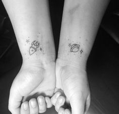 two people holding hands with small tattoos on them