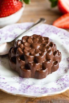 a chocolate dessert on a plate with strawberries in the background