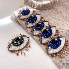 three pairs of blue and white beads on top of a piece of lace next to a pair of earrings