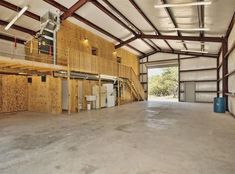 an empty garage with wood paneling on the walls and doors open to let in plenty of light