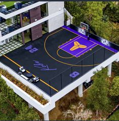 an aerial view of a basketball court in the middle of a building surrounded by trees