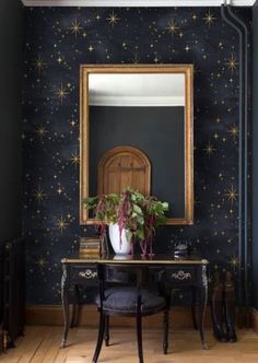 a desk with a mirror and potted plant on it in front of a star patterned wall