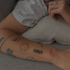 a person sitting on a couch with a tattoo on their arm that says vibes