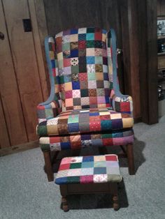 a patchwork chair and footstool in a room with wood paneling on the walls