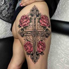 a woman's thigh with roses and a cross tattoo on the side of her leg