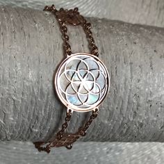 "Seed of Life bracelet in 18 carat rose gold on 925 silver and acquamarine mother of pearl background. The symbol commonly referred to as the Seed of Life is made up of seven circles; one in the center, and six others placed around it according to ancient spiritual traditions. It's tought that the seven interlocking circe are compared to the seven days of creation, with the different circles being ascribed to different points in the universe's making. The flore blooming in the middle is consider Spiritual Rose Gold Jewelry For Meditation, Adjustable Spiritual Rose Gold Jewelry, Adjustable Rose Gold Moonstone Jewelry, Seven Days Of Creation, Pearl Background, Sacred Jewelry, Meditation Accessories, Days Of Creation, Seed Of Life