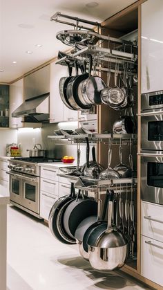 an organized kitchen with pots and pans hanging from the rack in front of the oven