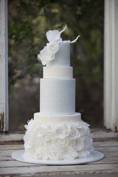 a three tiered white wedding cake with flowers