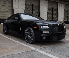 a black rolls royce parked in front of a building