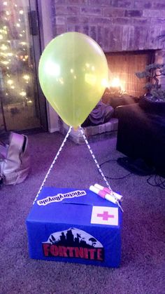 a box with a balloon attached to it sitting on the floor in front of a fireplace