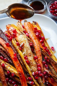 carrots with pomegranate and cinnamon on a white plate next to sauce