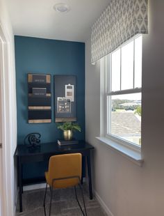 a room with a desk and chair next to a window that has a blue wall behind it