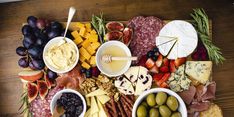 an assortment of cheeses, fruits and meats on a platter with olives