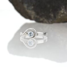 This ring incorporates a delicate swirl of silver emanating out from a sparkling gemstone, before wrapping back on itself as it falls around the side of the band. The Spiral ring is dainty and elegant when worn alone; but this slender stacking ring is designed to nestle closely with one or more accompanying bands. This sparkly sky blue topaz and sterling silver ring is handcrafted and made to order. Wear it by itself, or customize a stack of skinny bands and coordinating gemstone rings - the pos Modern Twist Anniversary Ring With Tension Setting, Modern Twist Ring With Tension Setting For Anniversary, Modern Twist Sterling Silver Diamond Ring As Gift, Silver Jewelry With A Modern Twist, Modern Twist Silver Jewelry With Round Cut, Modern Silver Jewelry With Round Cut, Modern Twist Sterling Silver Bypass Ring For Anniversary, Modern Twist Silver Bypass Ring For Anniversary, Modern Silver Bypass Ring For Anniversary