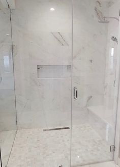 a walk in shower sitting next to a white tiled wall and floor with glass doors