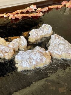 four doughnuts are being cooked on a grill with other pastries in the background