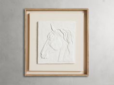 a white horse is in a wooden frame on the wall next to a gray wall