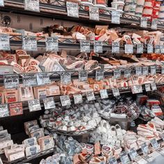 an assortment of meats and cheeses on display in a grocery store with price signs